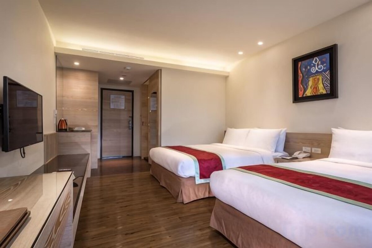 Una habitación de hotel con dos camas, un televisor y un escritorio.