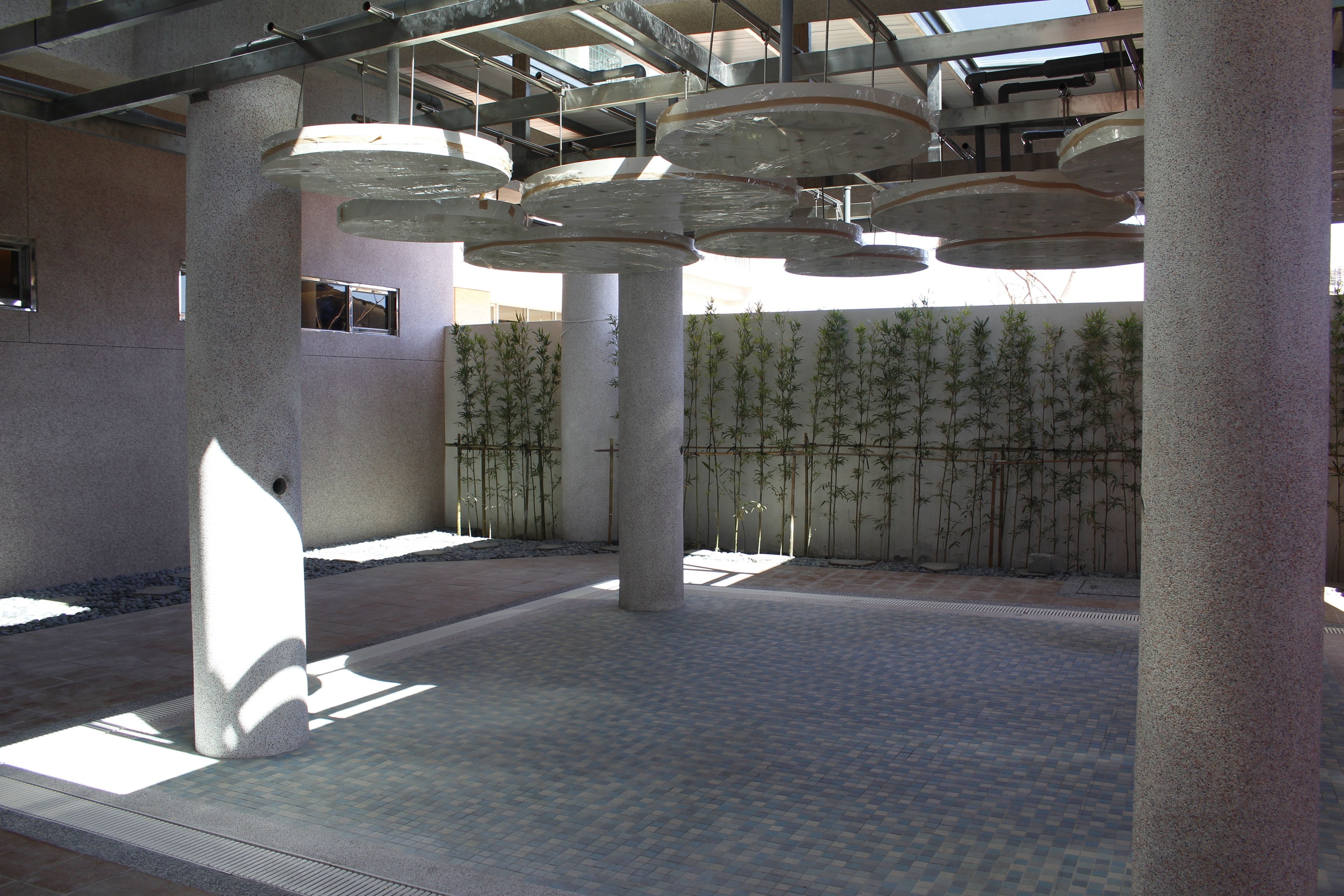 Amplio espacio interior con columnas imponentes, suelo de baldosas y pared de bambú.