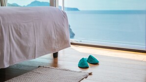 A bedroom with a bed, a view of the sea, and a pair of slippers on the floor. - Villa Fiorella Art Hotel (Massa Lubrense)