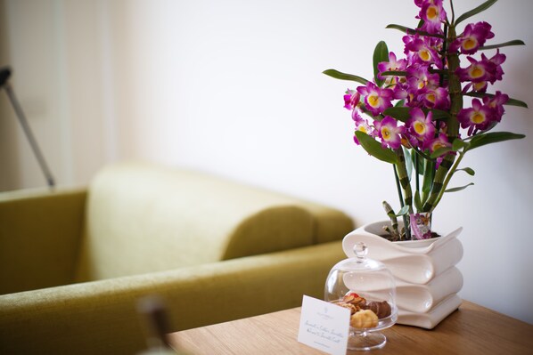 A table with a potted orchid plant and a glass dome containing cookies.