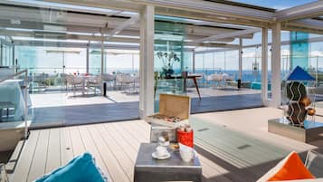 Relax in the open-plan lounge with ocean views, featuring a sofa, chairs, and dining table.