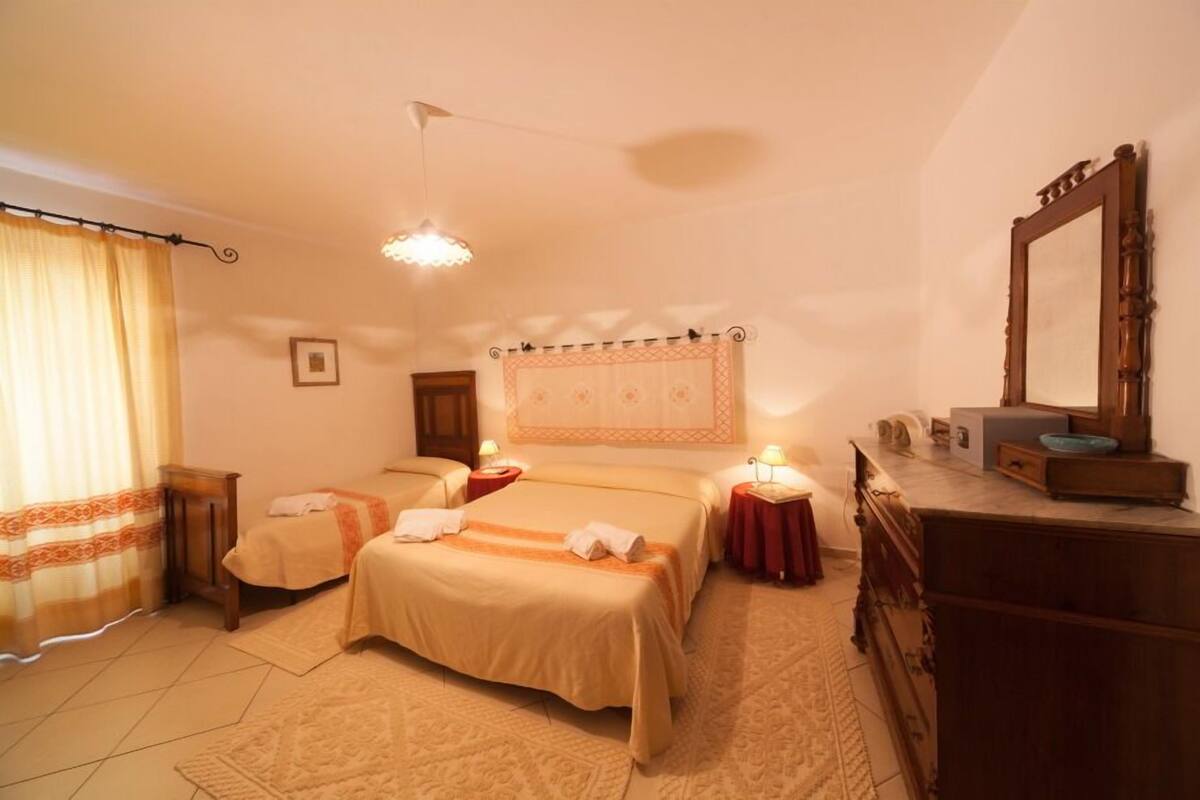 Habitación de hotel con dos camas, una cómoda, un espejo y una lámpara en el techo.