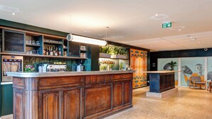 A bar area with a wooden counter, shelves with bottles and glasses, and a decorative wall with plants. - B&B HOME Paris Mairie de Saint-Ouen (Saint-Ouen)
