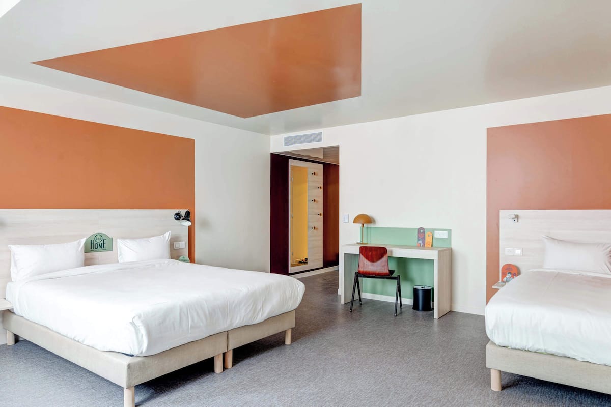A hotel room with two beds, a desk, and a chair.