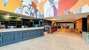 A modern bar area with a wooden counter, seating area, and a mural on the wall. - B&B HOME Paris Mairie de Saint-Ouen (Saint-Ouen)