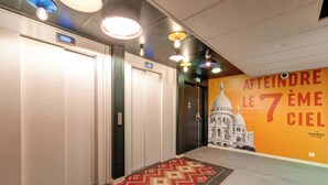 A hotel hallway with patterned carpet, multiple doors, and a large mural of a building. - B&B HOME Paris Mairie de Saint-Ouen (Saint-Ouen)