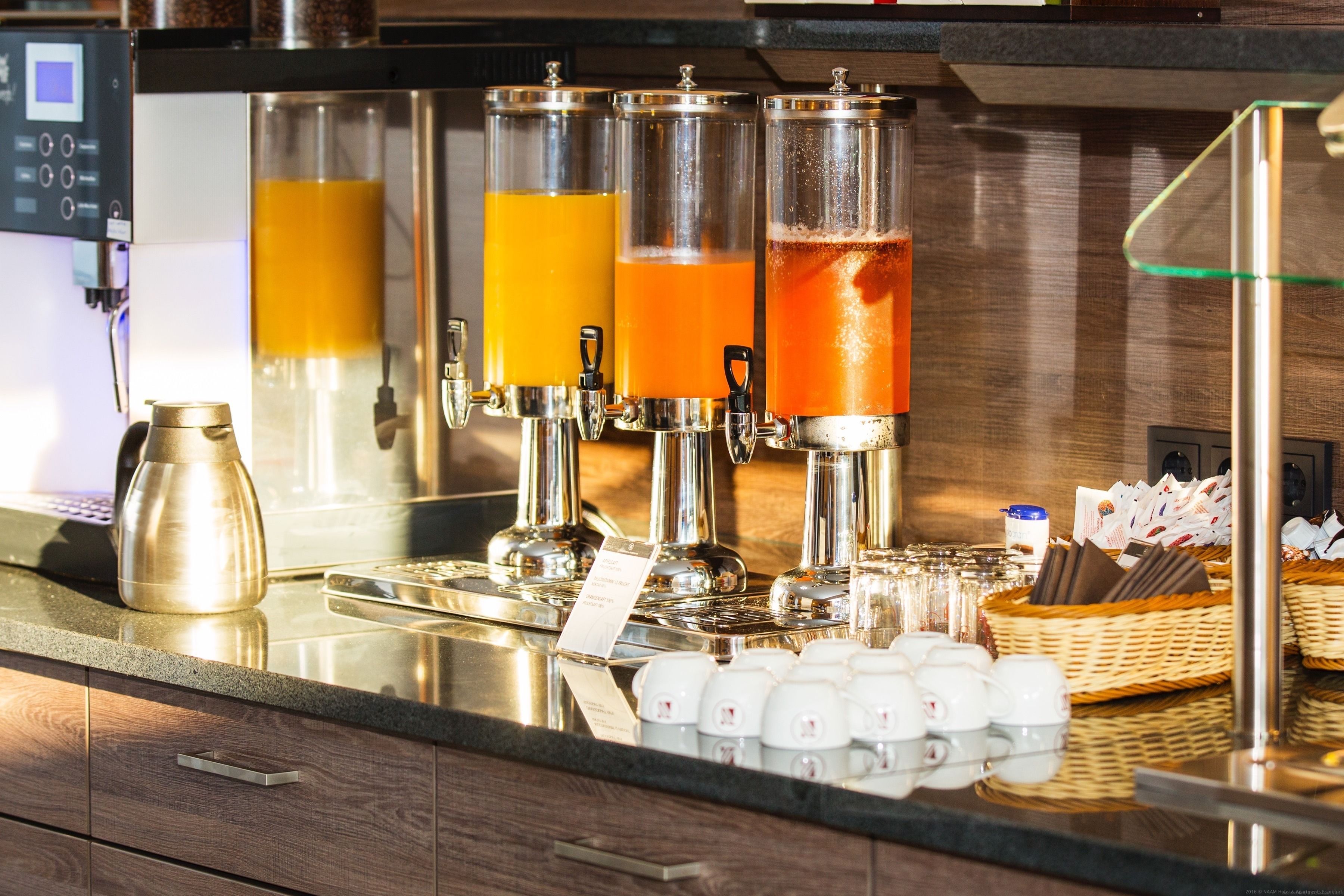 A beverage station with multiple dispensers, a coffee pot, and a basket of napkins.