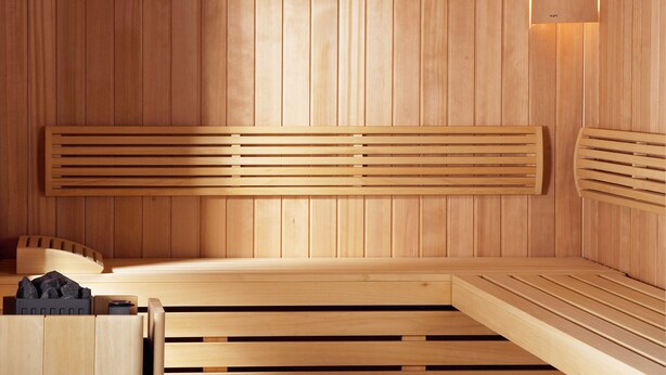 Sauna, jossa on puiset penkit ja seinälle kiinnitetty kello.