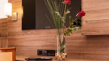 Una scrivania di legno per la reception, con un vaso di fiori, un telecomando e un display digitale.