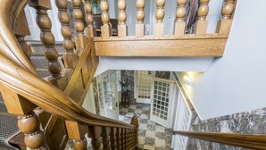A wooden staircase with a checkered floor and a view of a room with a door and a plant. - Boutique Hotel Het Scheepshuys (Breda)
