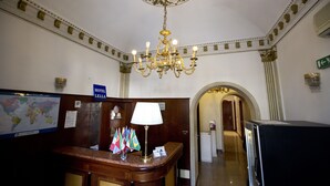 A hotel reception area with a chandelier, a desk with a lamp, flags, and a world map. - Hotel Lella (Rome)