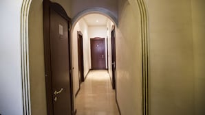 A hallway with a wooden door on the left, a tiled floor, and an arched ceiling. - Hotel Lella (Rome)