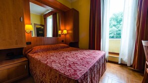 A hotel room with a large bed, wooden wardrobe, and a mirror above the bed. - Hotel Lella (Rome)