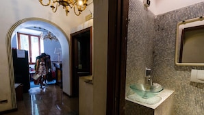 A hallway leading to a bathroom with a glass sink and tiled walls. - Hotel Lella (Rome)