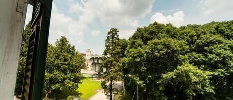 Une vue d’un parc verdoyant et luxuriant, avec une statue visible au loin, entourée d’arbres.