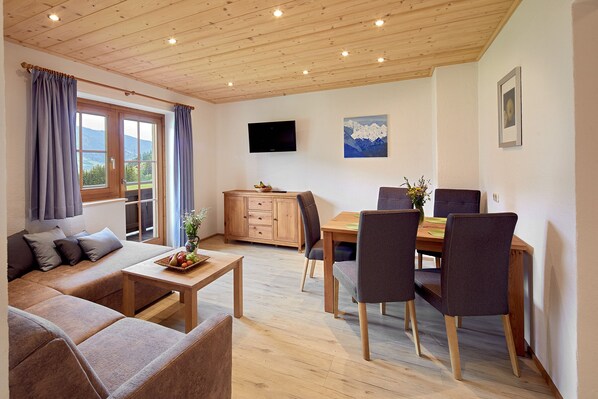 A cozy living room with a sofa, coffee table, and dining area with chairs and a table.