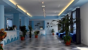 Un hall d’hôtel avec un sol à carreaux, des murs bleus et des plantes en pot.