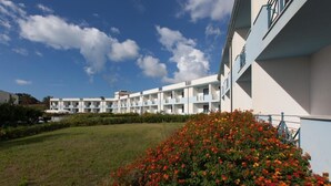 Un hôtel à plusieurs étages, doté d’une rangée de balcons et d’une pelouse bien entretenue.