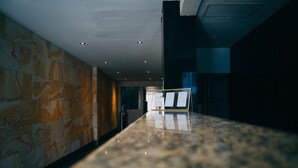 A modern hotel lobby with a marble reception desk, stone walls, and recessed lighting. - Hotel Villamar (Veracruz)