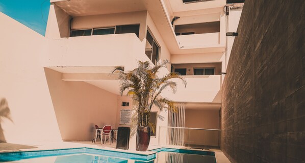 Un área de piscina con una palmera, una silla y una mesa.