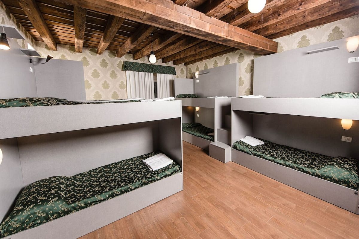 A room with bunk beds, wooden beams, and patterned wallpaper.