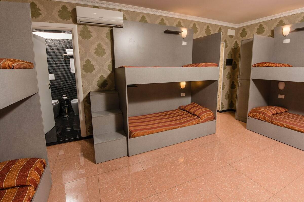 A room with bunk beds, a small staircase, and an air conditioning unit.