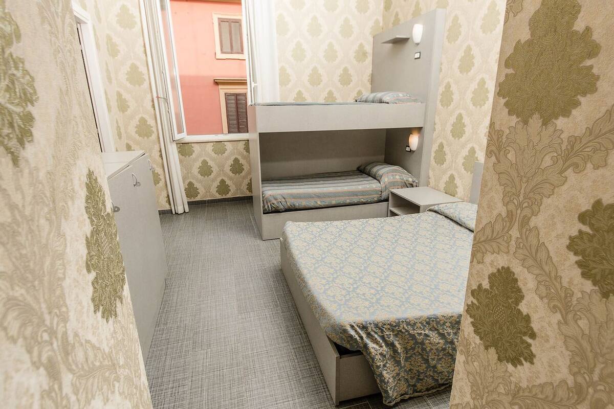 A compact bedroom with bunk beds, a small desk, and a wardrobe.