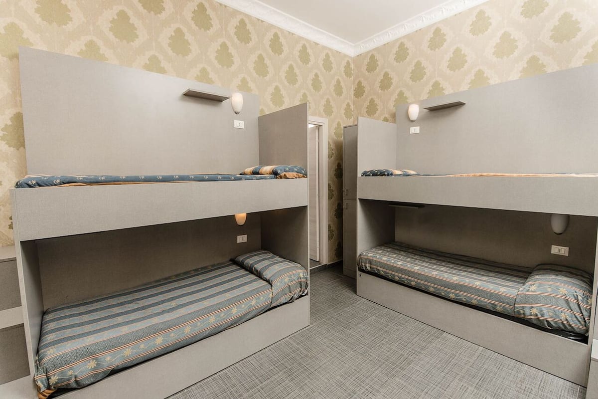 A room with two bunk beds, each with a pillow and a blanket.