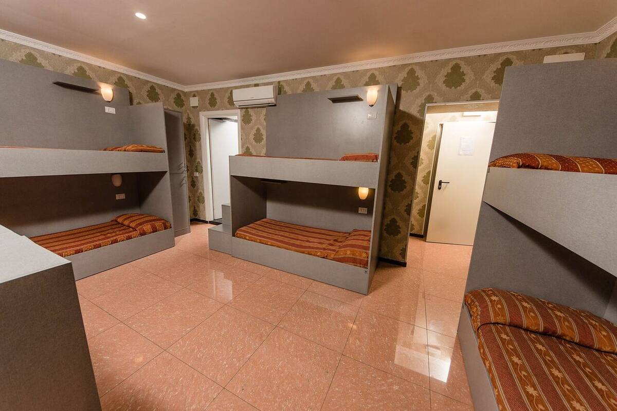 A room with bunk beds, a tiled floor, and an air conditioning unit.