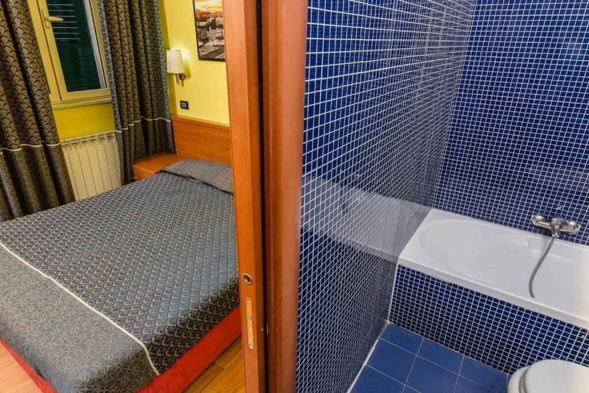 A small, compact room with a bed, a shower area, and a toilet.