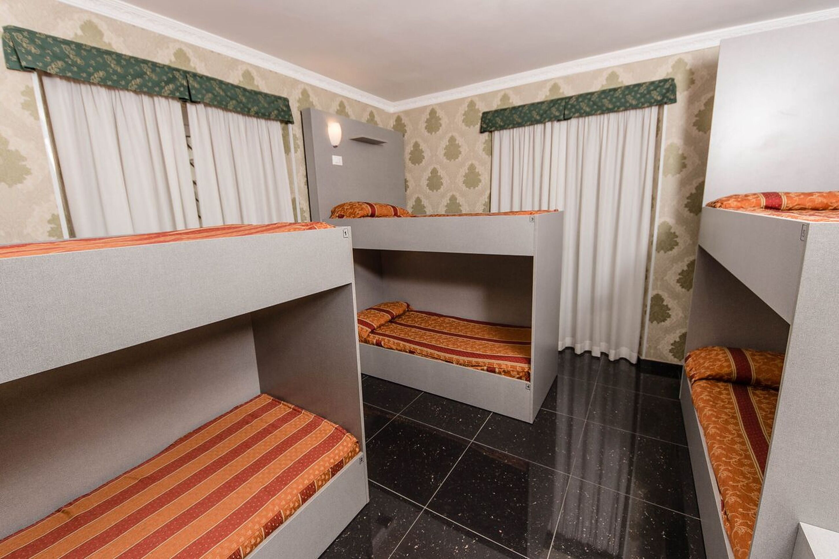 A room with bunk beds, a small table, and a window with curtains.