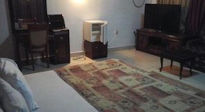 A bedroom with a bed, a desk, a chair, a television, and a wardrobe.