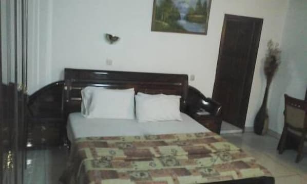 A bedroom with a wooden bed, white pillows, and a patterned bedspread.