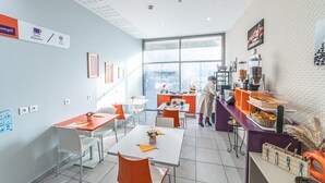 Un'area colazione moderna con buffet, sedie bianche e arancioni, e un'ampia finestra che offre vista all'esterno.