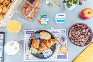 A breakfast setting with croissants, a bowl of chocolate cereal, a glass of orange juice, and various breakfast items on a table. - Montempô Marseille Centre Euromed (Marseille)