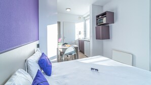 Una camera d'albergo con un letto, una scrivania e un angolo cottura.