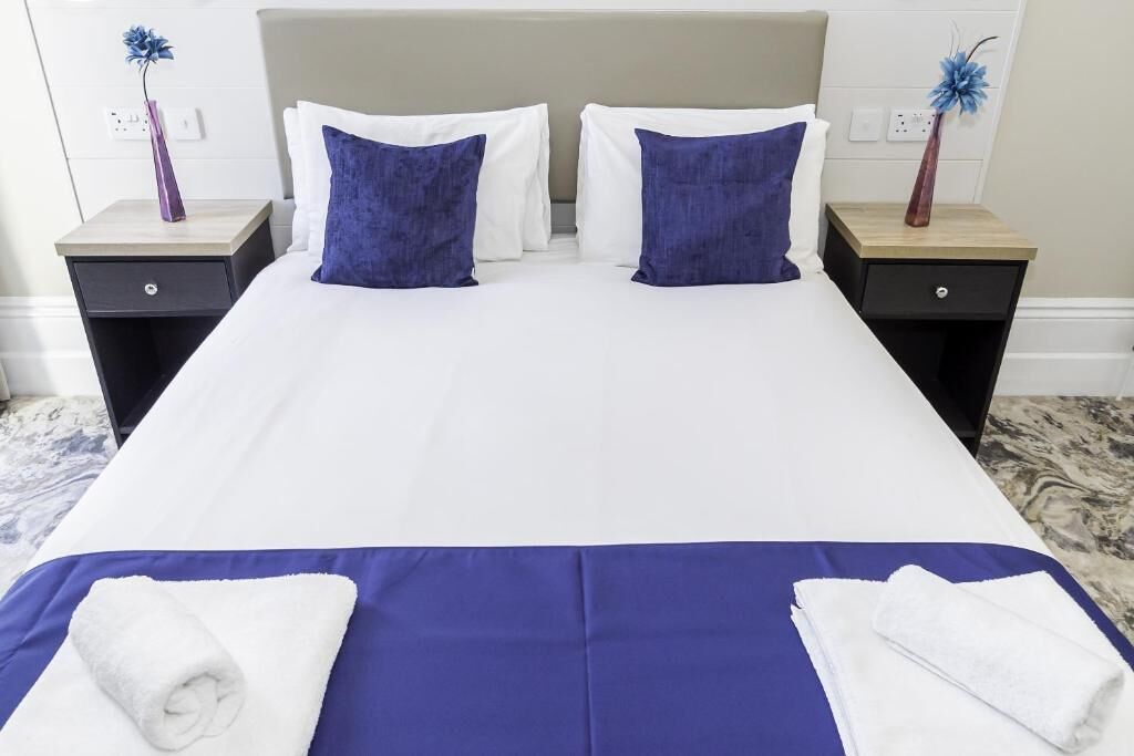 Une chambre d’hôtel avec un grand lit, deux tables de chevet et un sol en marbre.