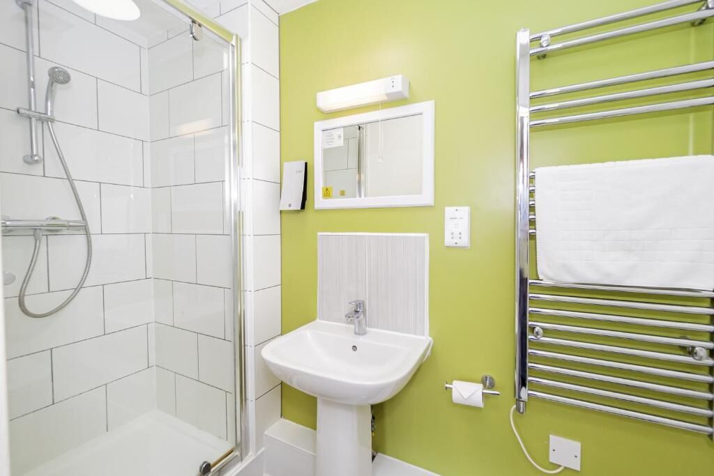 A bathroom with a shower, sink, and towel rack.