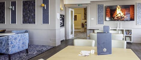 A hotel lobby with a reception desk, seating area, and a fireplace.