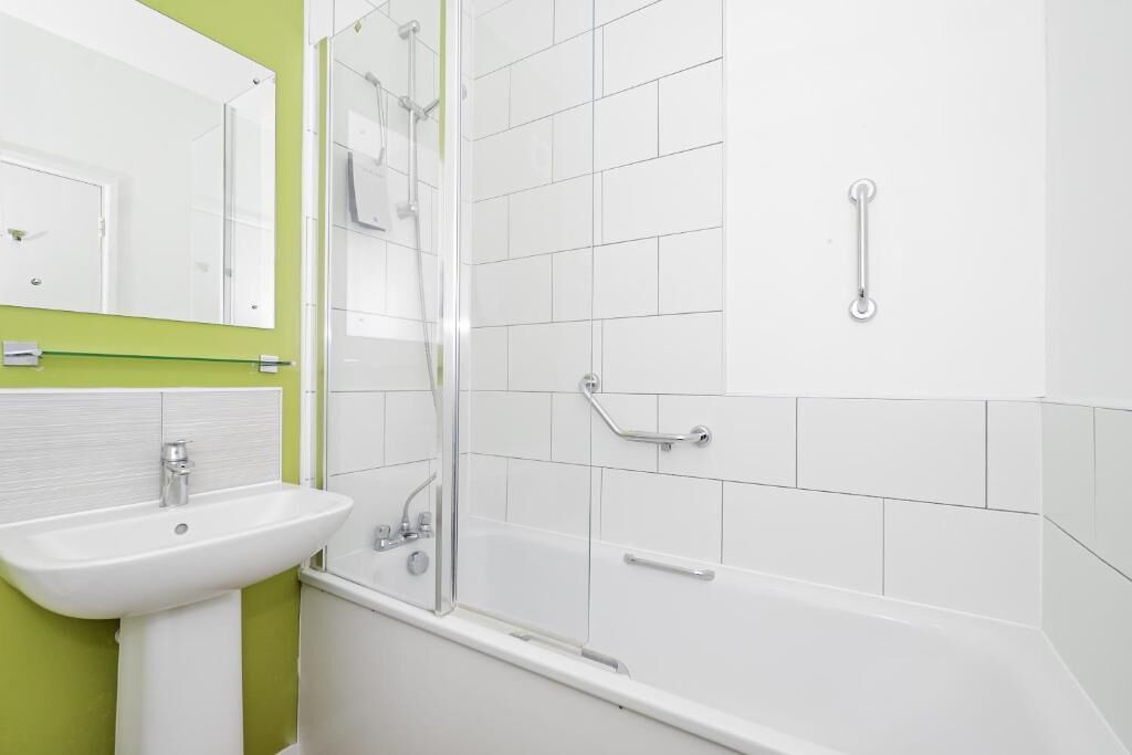A bathroom with a white sink, mirror, and shower area.
