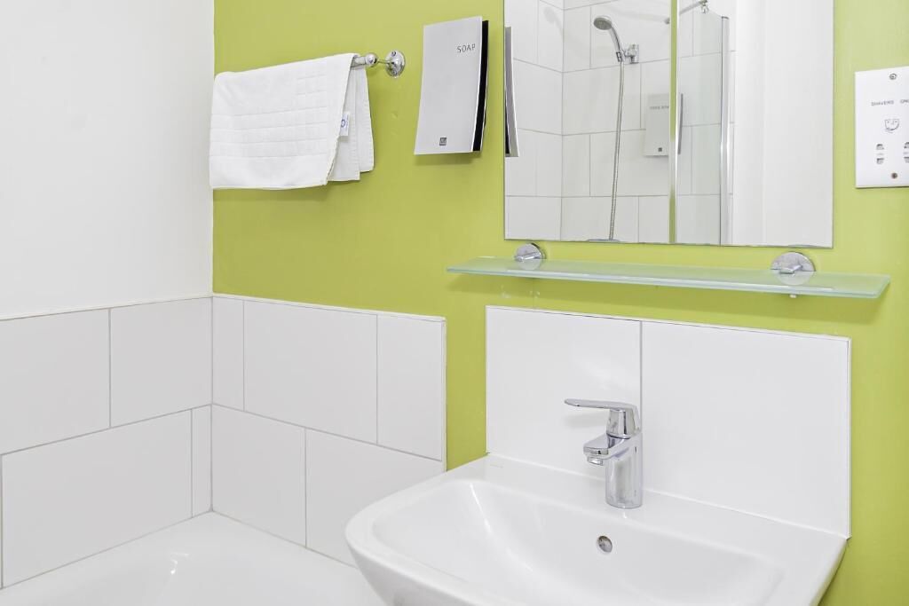 A bathroom with a white sink, a mirror, and a shower.