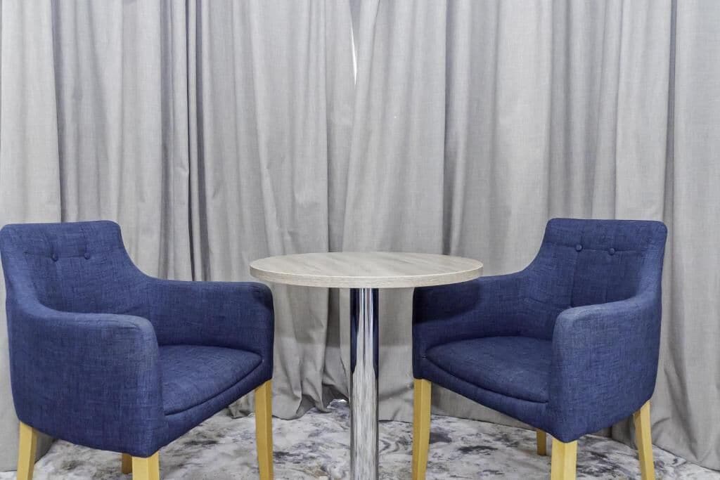 Una habitación con dos sillones tapizados en azul y una mesa redonda con superficie clara.