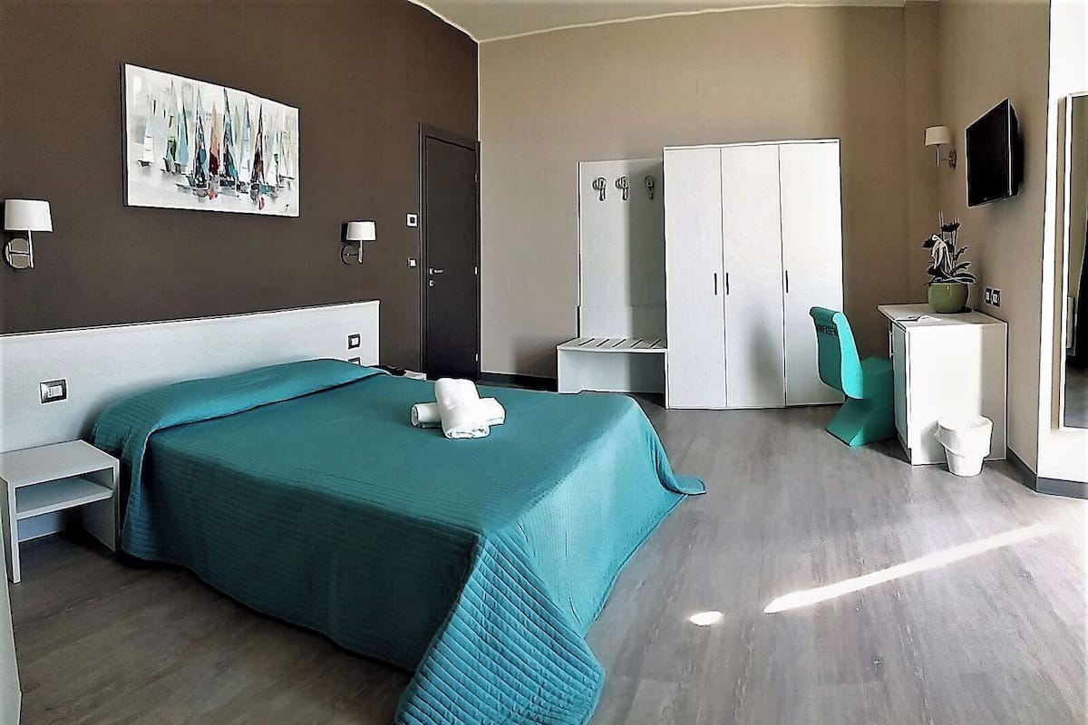 Une chambre d’hôtel équipée d’un lit, d’un bureau, d’une armoire, d’une chaise et d’un téléviseur.