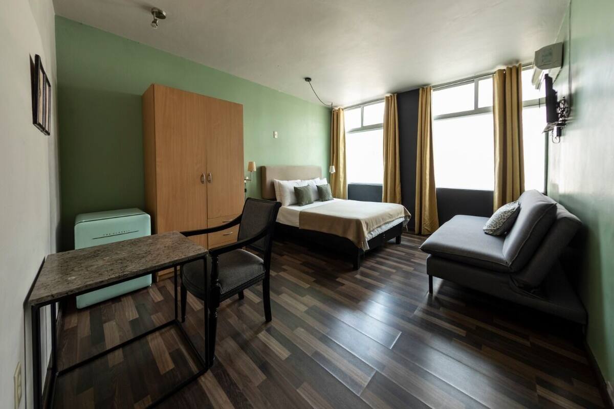 Een kamer met een bed, een slaapbank, een bureau en een kledingkast.