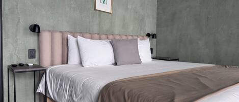 Quarto moderno com cama, mesa de cabeceira e luminária na parede.