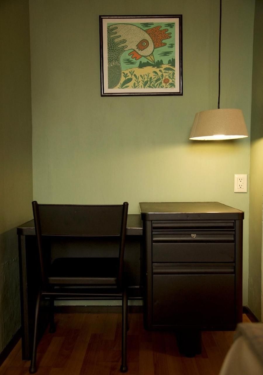 Una habitación con escritorio, silla y lámpara.