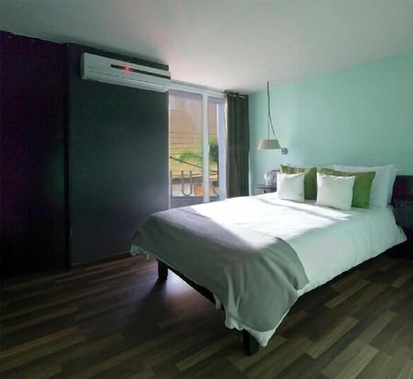 Un dormitorio con cama, ventana y aire acondicionado.
