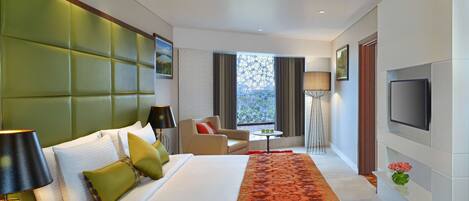 Habitación de hotel con una cama grande, un sofá, un televisor y una ventana con vistas.