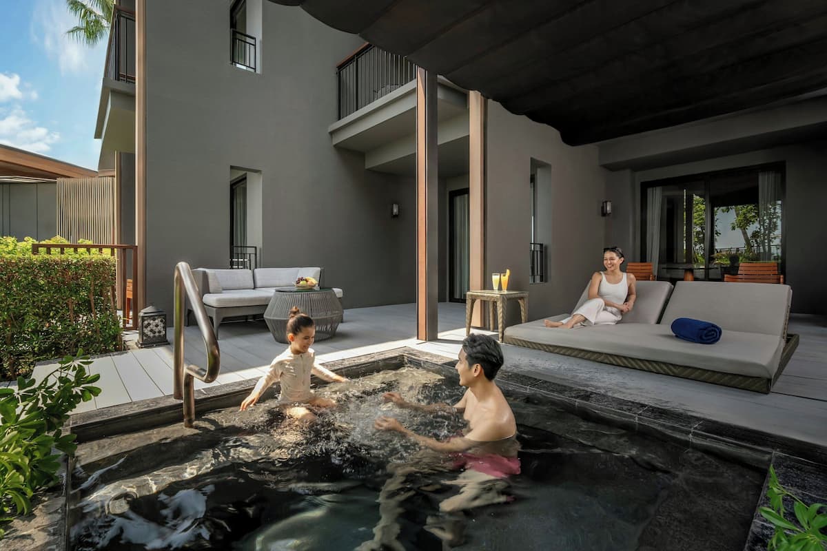 Een moderne buitenzwembad met een jacuzzi, zitplaatsen en een overdekt terras.
