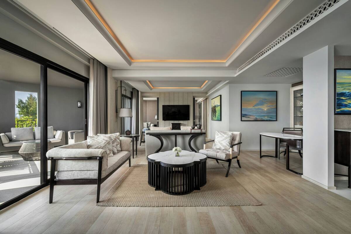 Een moderne woonkamer met een bank, fauteuils, een salontafel, een televisie en kunstwerken aan de muren.
